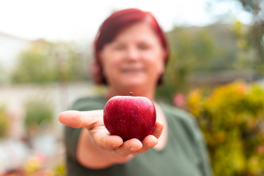 mature woman is holding a red apple in her hand. health and healthy eating concept