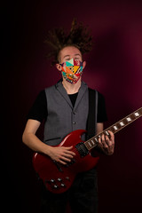 Coronavirus, quarantine at home, playing guitar in protection mask