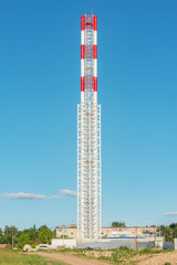 Obraz premium Metal chimney by the construction site at sunset time.