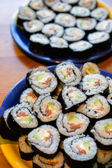 Two round plates of homemade sushi maki with salmon, rice and avocado