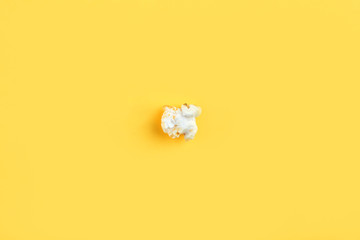 Caramel popcorn isolated on a yellow background, scattered. Mockup, frame of popcorn, top view.