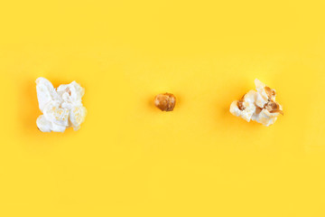 Caramel popcorn isolated on a yellow background, scattered. Mockup, frame of popcorn, top view.