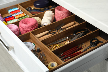 Fototapeta na wymiar Sewing accessories in open desk drawer indoors, closeup