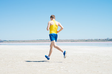 young man jogging on the beach in summer