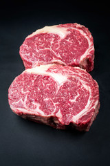 Obraz premium Raw dry aged wagyu entrecote beef steak as closeup on a black background with copy space
