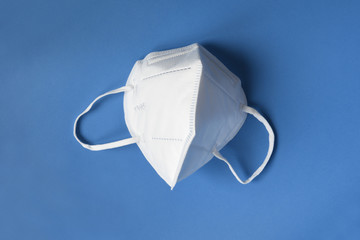 detail of white mask KN95 or N95 for protection against coronavirus on a blue background. Prevention of the spread of viruses and pandemic COVID-19.