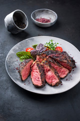 Barbecue dry aged wagyu entrecote beef steak with lettuce and tomatoes as closeup on a modern...