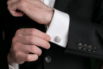 Close-up of a man in a tux fixing his cufflink. groom bow tie cufflinks