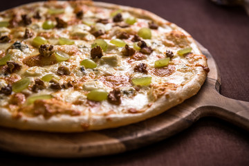 Pizza with various cheese, walnuts and grapes