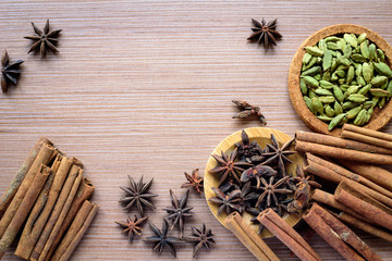 Star anise, cinnamon sticks and cardamom on a wooden surface.