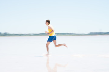 Fototapeta na wymiar Young male runner running on a empty beach at dawn. Blur effect.