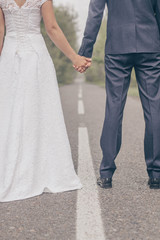 Wedding couple together walking by park alley. Wedding photography with unrecognizable groom an bride.