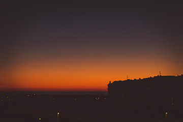 Sun behind buildings in a sunrise, with very orange colors