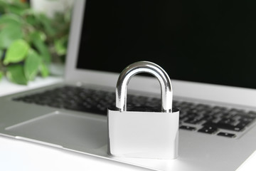 Metal lock and laptop on table, closeup. Protection from cyber attack