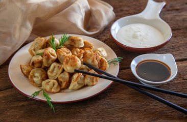 Dumplings with meat, onion and sour cream, on wooden background