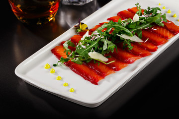 Smoked salmon plating with arugula leaves on top. Elegant plating of asian menu dish. Food photography in fine dine in table perfect concept for magazine or restaurant’s menu book.