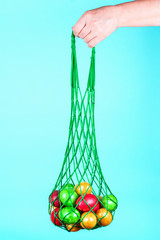 A woman's hand holds Easter eggs in a vintage bag on a delicate mint background. Minimal Easter concept. Copy space