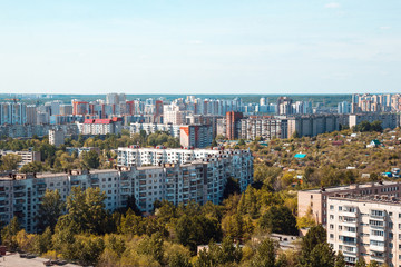Fototapeta na wymiar Multi-storey concrete residential buildings and a forest Park against the sky in a big city in the daytime. Architecture and real estate in the metropolis