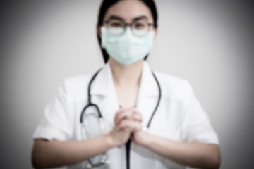Blur for background Asian woman doctor wear mask hand clasp gesture of begging for help, Let's cooperate, work together, confederate, help each other to stop the epidemic of the Corona Virus concept