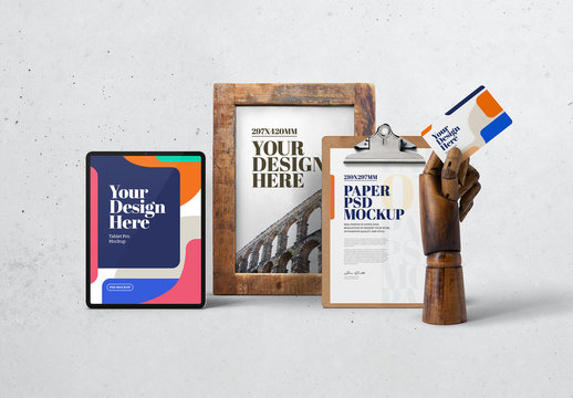 Wooden Hand Holding Business Card with Poster Frame, Tablet, and Clipboard Mockup