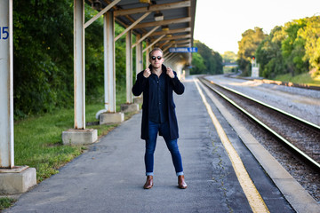 Man standing next to old urban train tracks wearing black coat