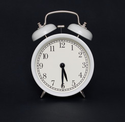 Old-style alarm clock, black and white, it's half past five.