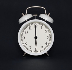 Old-style alarm clock, black and white, it's six o'clock.