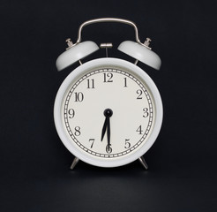 Old-style alarm clock, black and white, it's half past six.