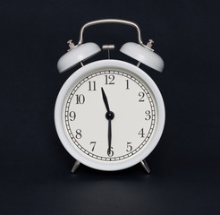 Old-style alarm clock, black and white, it's half past eleven.