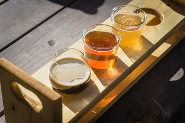 Mixed of hand-crafted beverages on tasting tray paddle with beer name in natural setting