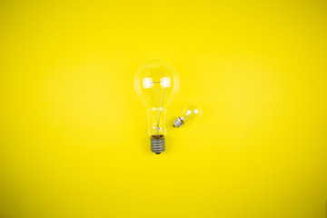 Two bulbs - large and small. Yellow background
