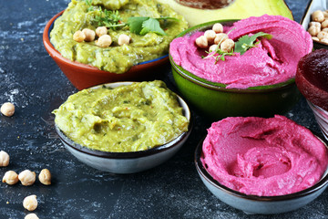 A variety of colored hummus, beetroot hummus, hummus with avocado on background. Veggie Clean...