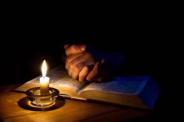 Hands folded in prayer over Scriptures