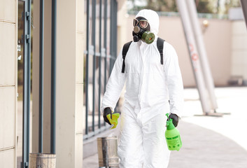 Quarantine, coronavirus infection. A man in protective equipment disinfects with a sprayer in the...