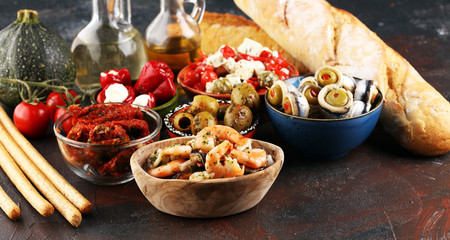 Antipasti Appetizer sweet cherry peppers stuffed with soft cheese feta, olives with oil. Seafood and anchovies with olives and dried tomatoes in oil