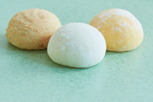 Closeup on three bright colorful mochis on a pastel green plate.