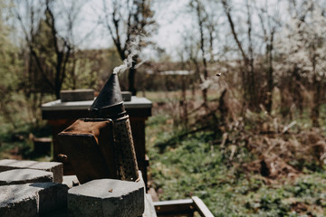 Chimney for flashing bees. Chimney stands near beehives.The beekeeper's tool. Bee smoker smoking.