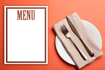 Elegant table setting and empty menu on orange background, flat lay. Space for text