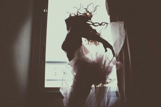 Low Angle View Of Woman Dancing Against Window At Home