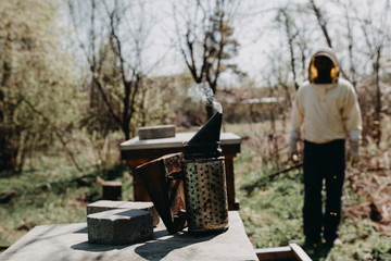 Chimney for flashing bees. Chimney stands near beehives.The beekeeper's tool. Bee smoker smoking.