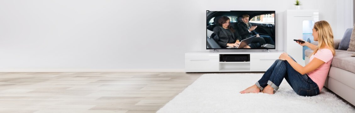Woman Sitting On Carpet Watching Television