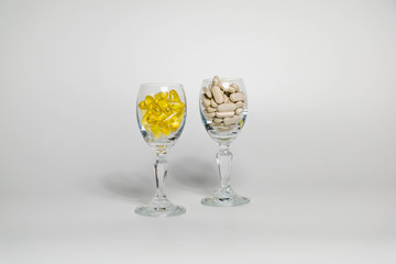 Two glasses full of capsules on a white background