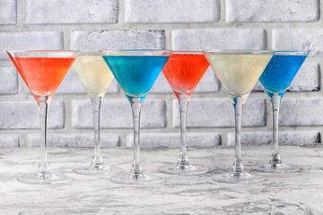 In martini glasses with a brilliant celebratory drink. Red, blue, white alcoholic drinks. Glitter drink.