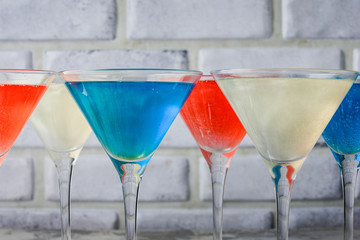 In martini glasses with a brilliant celebratory drink. Blue, white and red alcoholic drinks close-up. Glitter Drink.