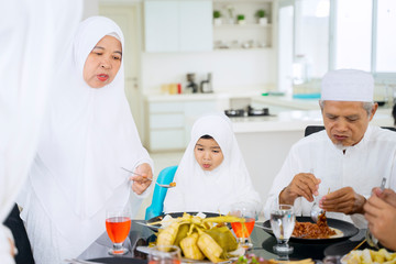 Little girl eating with grandfather and grandmother