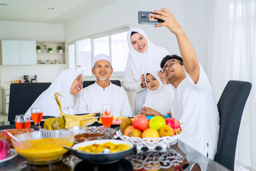 Muslim family taking selfie picture in dining room