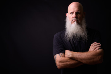 Mature bald bearded man against black background