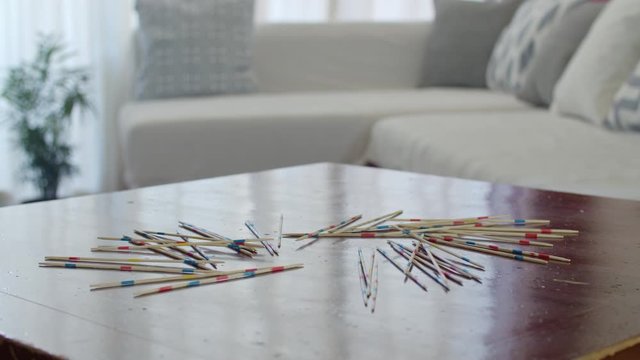 A young woman throwing the wood sticks on the table before starting a pick up sticks game. Filmed in slow motion (60fps)