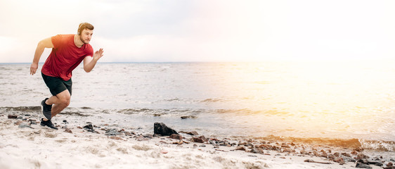 Sport lifestyle. Runner in motion. Athletic guy in sportswear runs very fast on the beach at sunset listening to his favorite music on headphones
