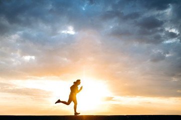 Attractive male runner in motion at sunset. Sport lifestyle. A man in sportswear and sneakers runs at sunset